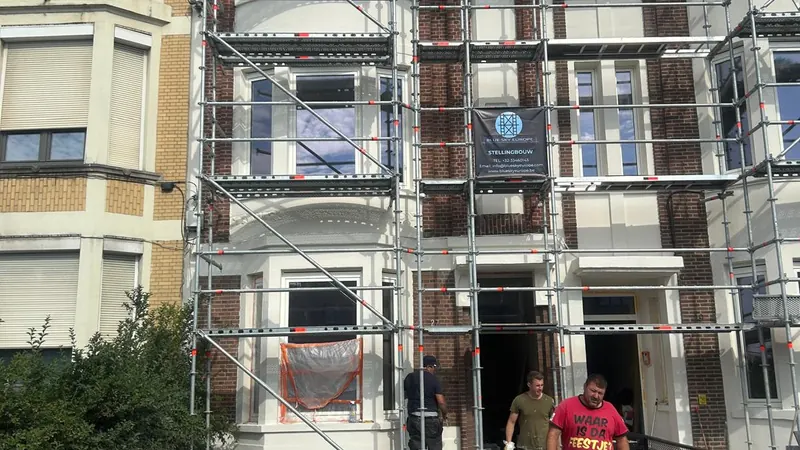 voorgevel van het gebouw in de steigers met de ploeg aan het werk, breed kader