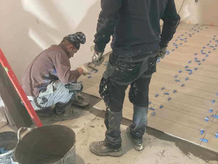 twee tegelzetters aan de vloer