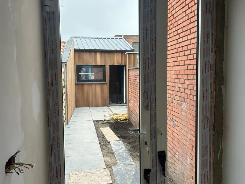 zicht door nieuwe deur naar tuin en garage met houten bekleding