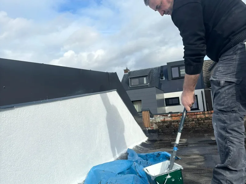 Vakman schildert de witte buitenmuur bij de totaalrenovatie in Bonheiden