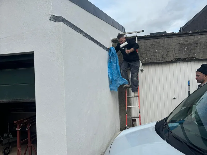vakman schildert de witte buitenmuur, ander punt van de gevel