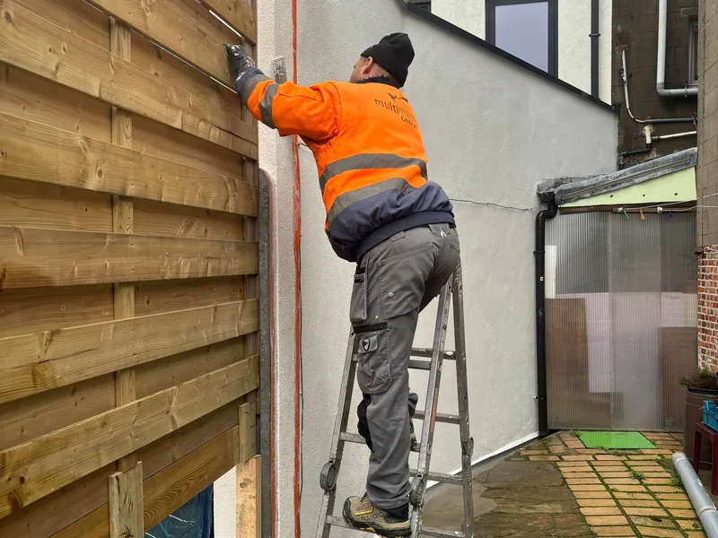 vakman schildert de plint van de witte buitenmuur