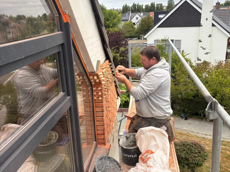 vakman metselt steenstrips rond driehoekraam