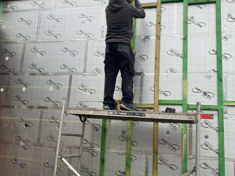 vakman op stelling plaatst gevelisolatie