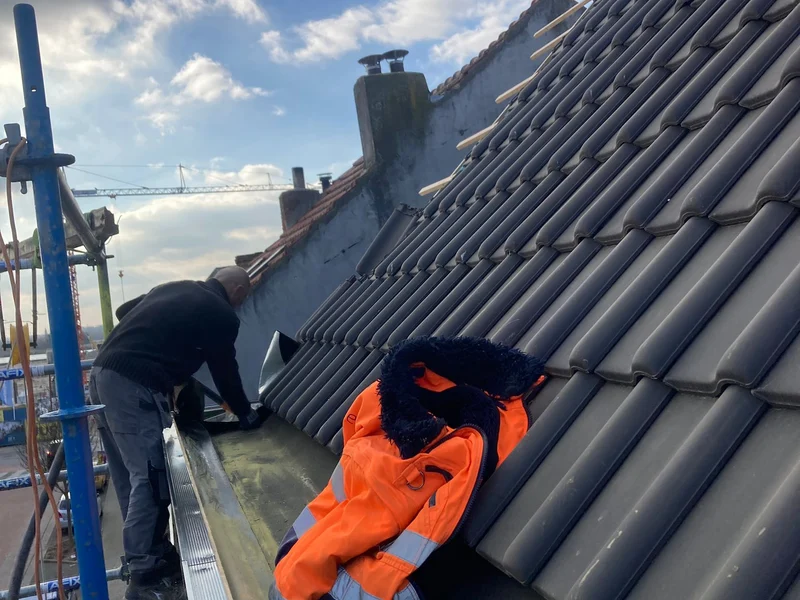 twee dakwerkers in fluo leggen pannen
