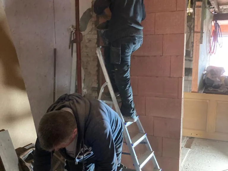 vakman metselt binnenmuur op ladder