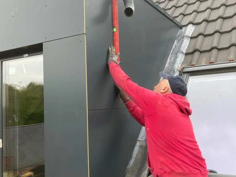 vakman in rood monteert Rockpanel op dakkapel