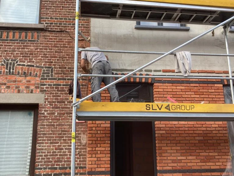 vakman op steiger zet steenstrips