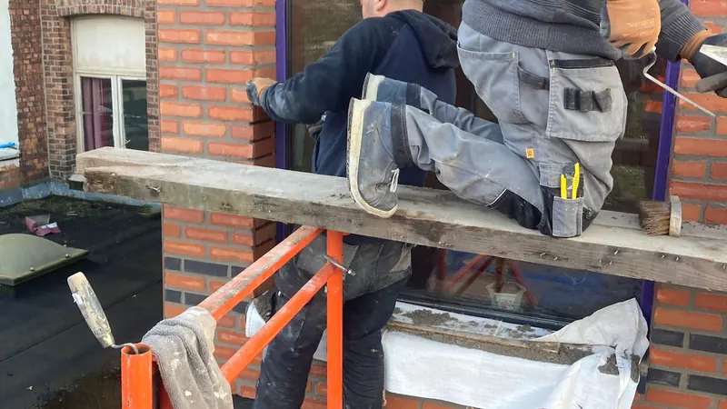 Afgewerkte achterbouw met rode steenstrips en grote zwarte ramen, project in Hemiksem