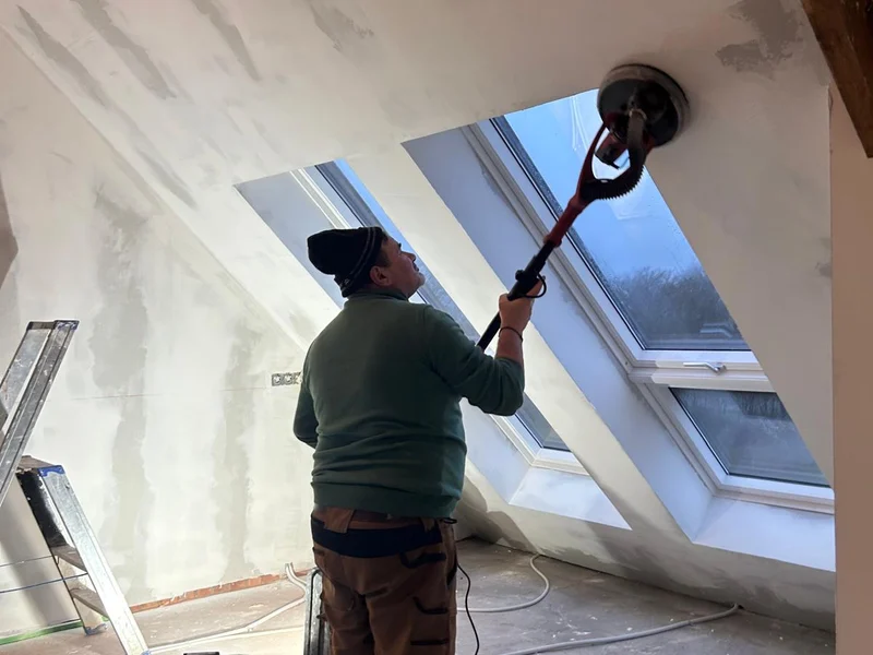 pleisteraar schuurt de zolderwand