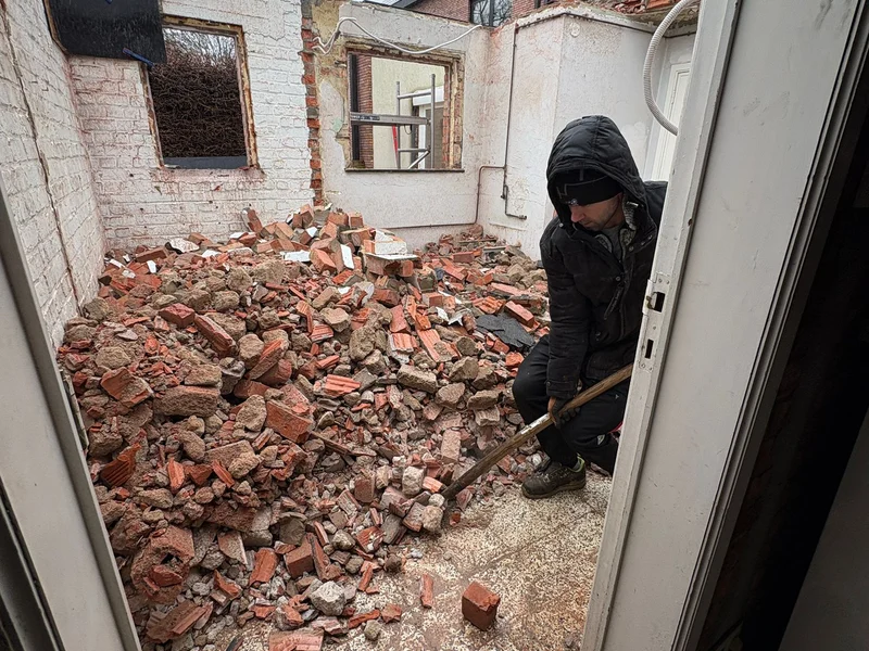vakman breekt dak van de aanbouw af