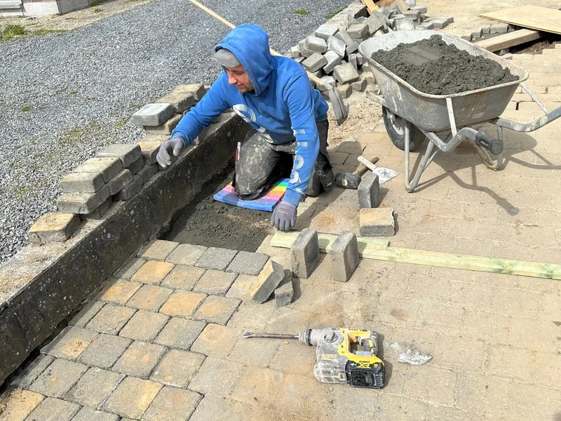 vakman in blauw metselt keermuur met blokken