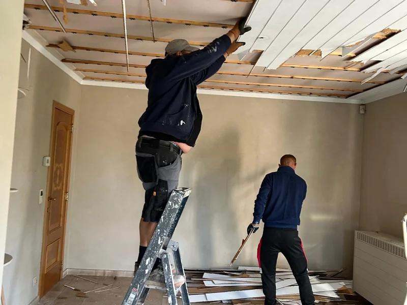 twee vaklui breken het oude plafond af