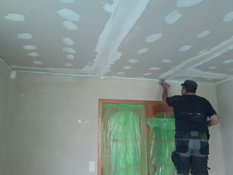vakman werkt muur af naast raam