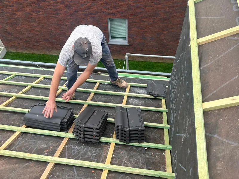 dakwerker stapelt nieuwe pannen op panlatten