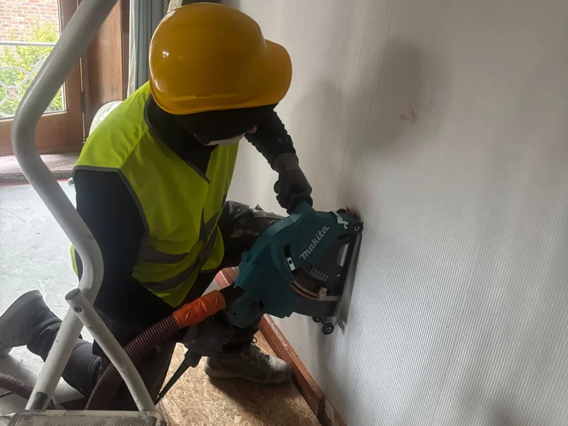 vakman met helm slijpt doorlatei