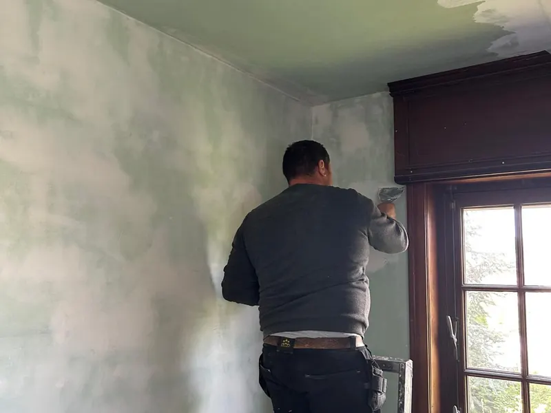 pleisteraar aan hoge muur