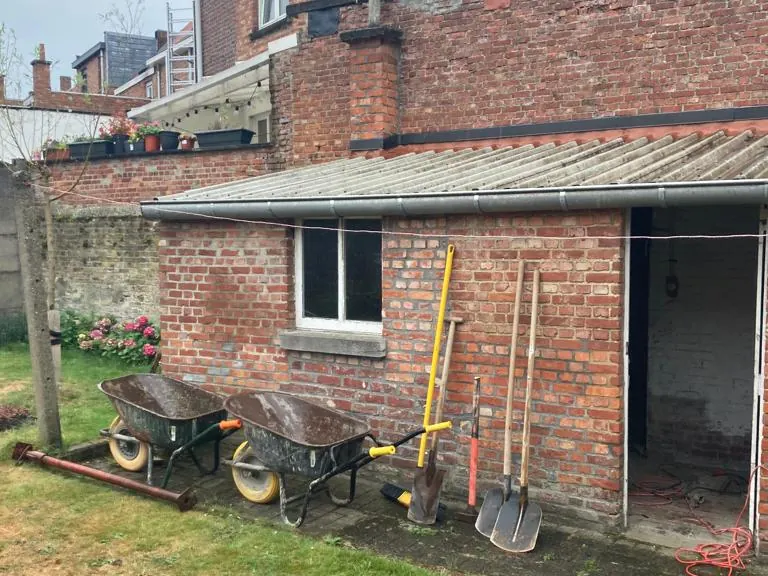 oude bakstenen aanbouw met golfplaten dak voor de werken