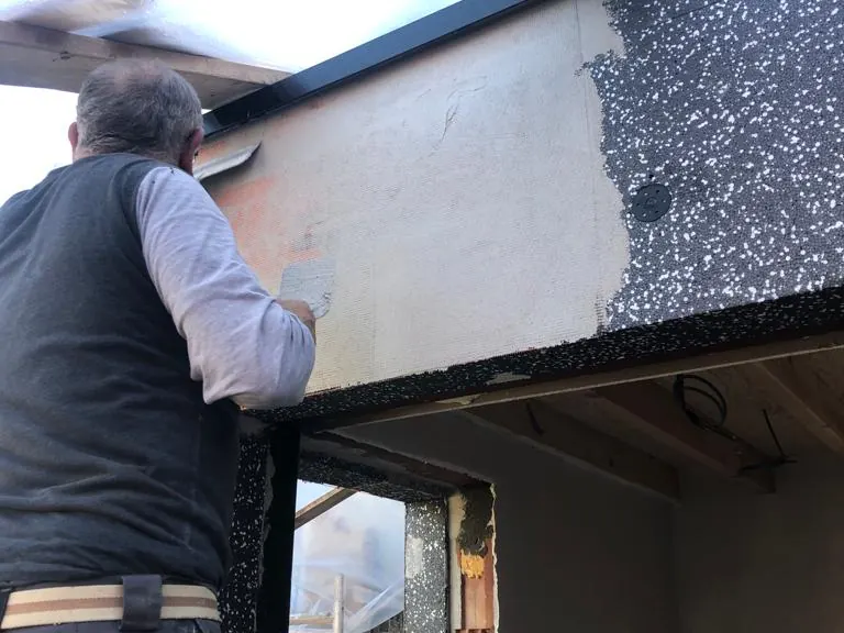 vakman plaatst gevelisolatie rond raamopening