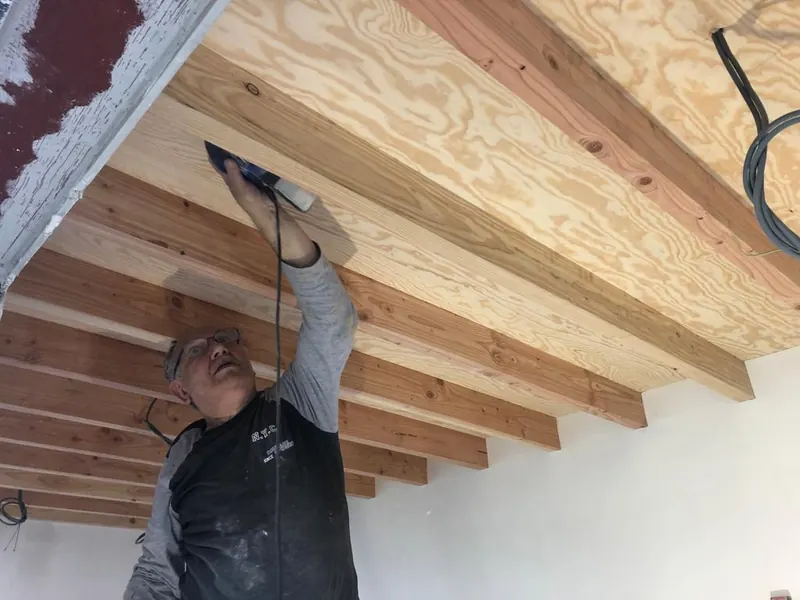 vakman werkt aan houten plafond met balken
