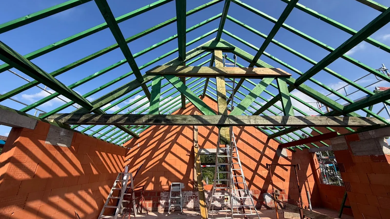 Groene stalen dakstructuur tegen een blauwe lucht boven de snelbouwmuren, project in Leuven
