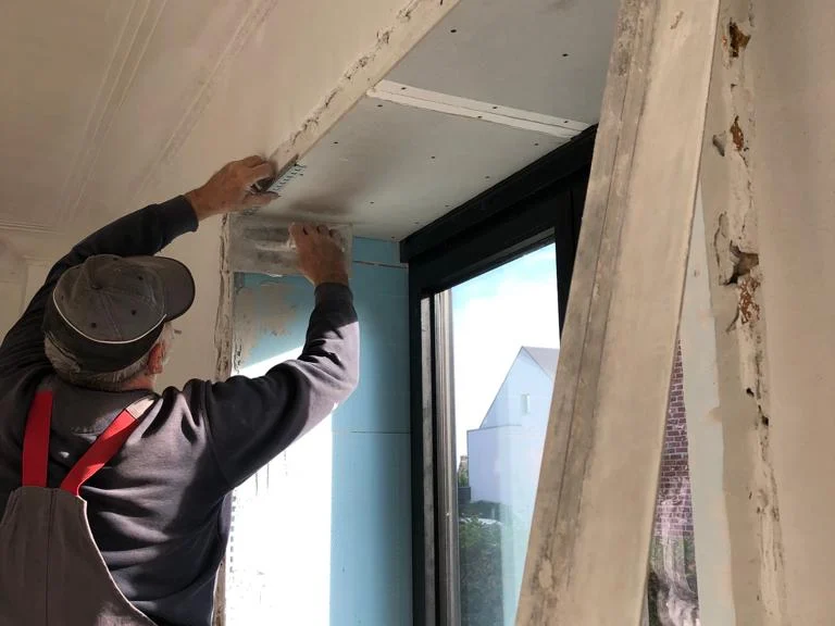vakman werkt raam af, tegenlicht