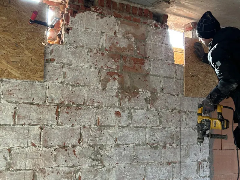 vakman maakt raamopening in bakstenen gevel