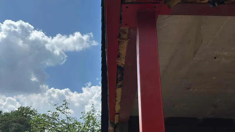rode stalen ligger en kolom tegen blauwe lucht met wolken, grafisch sterk