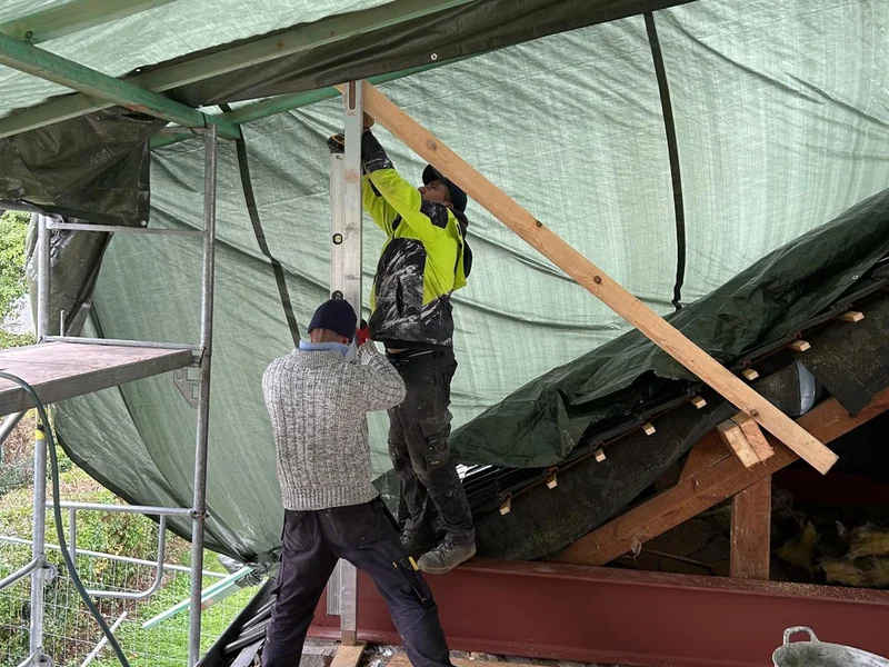 metselaars aan de nieuwe snelbouwmuur onder zeil