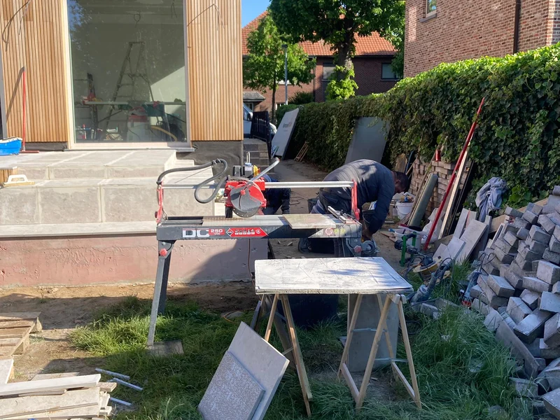 ploeg zaagt tegels voor terrastrap