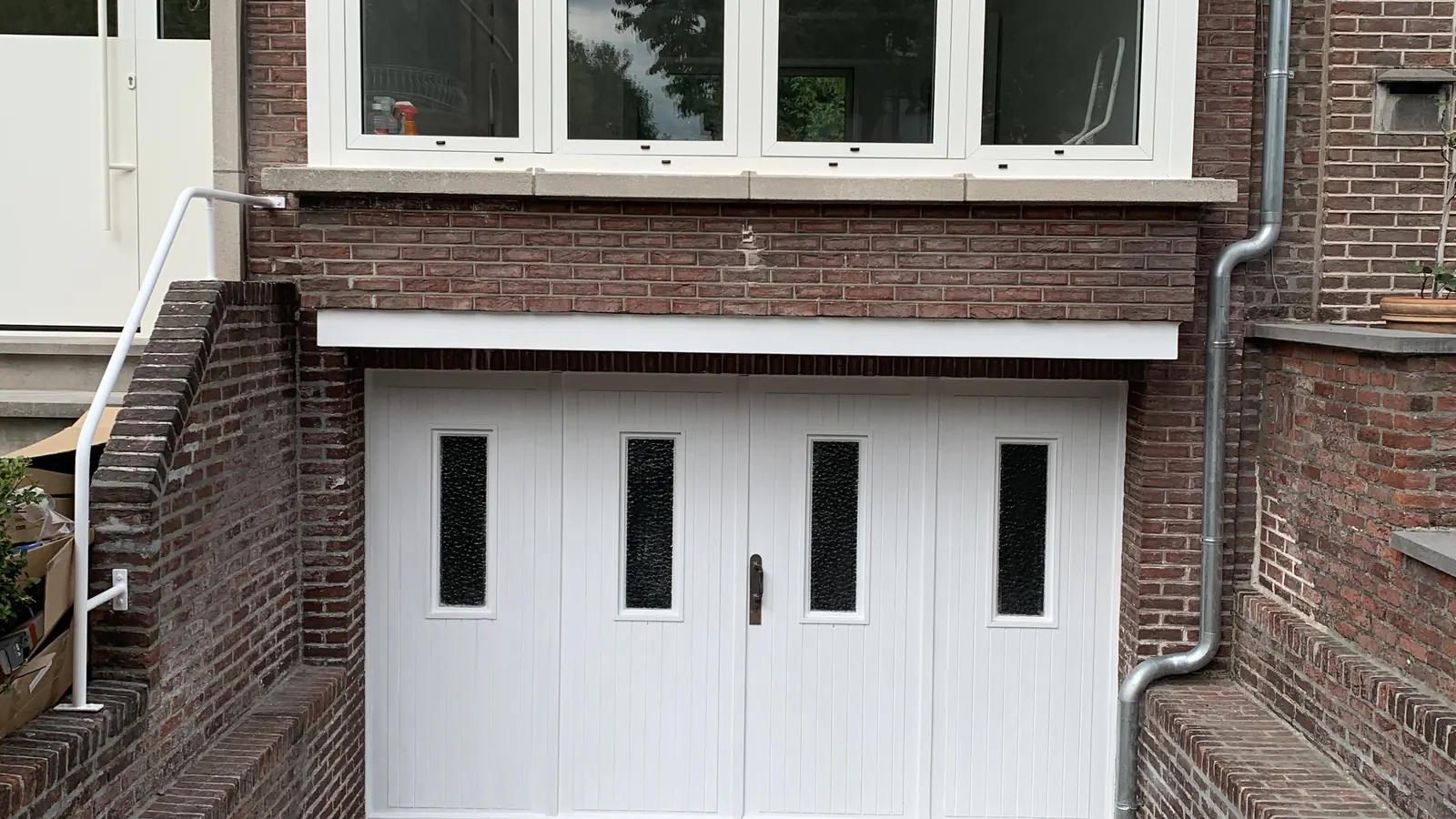 afgewerkte voorgevel met nieuwe ramen en twee witte garagepoorten, strak