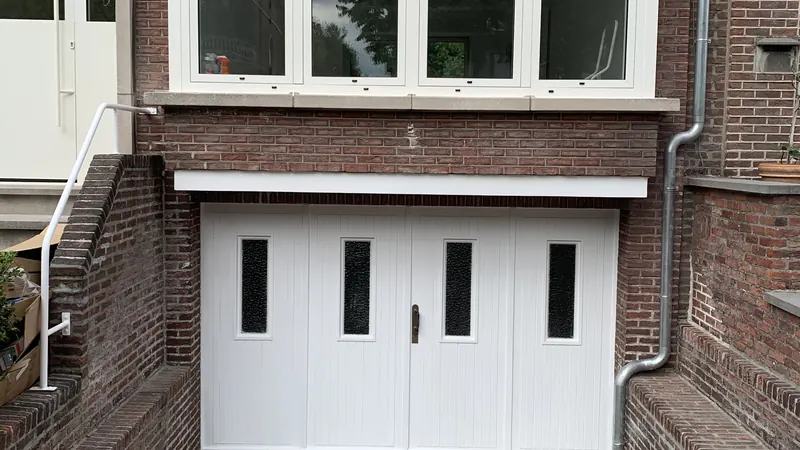 afgewerkte voorgevel met nieuwe ramen en twee witte garagepoorten, strak
