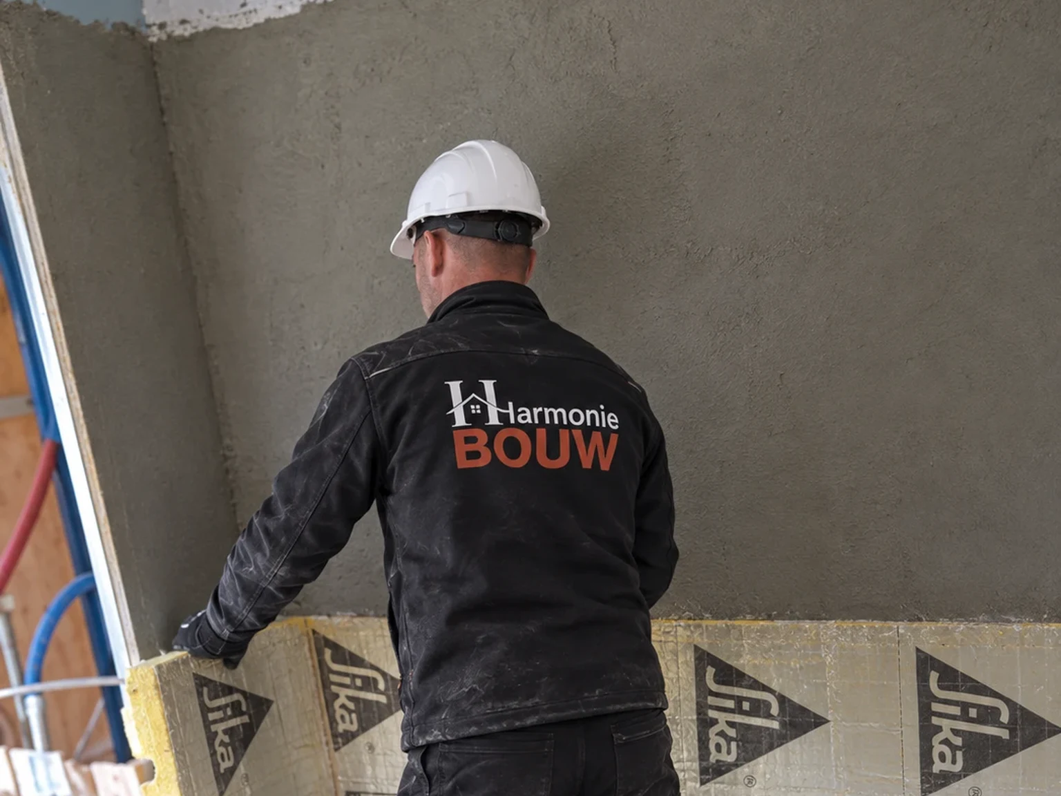 Vakman met helm en bedrijfskledij werkt de geïsoleerde gevel af